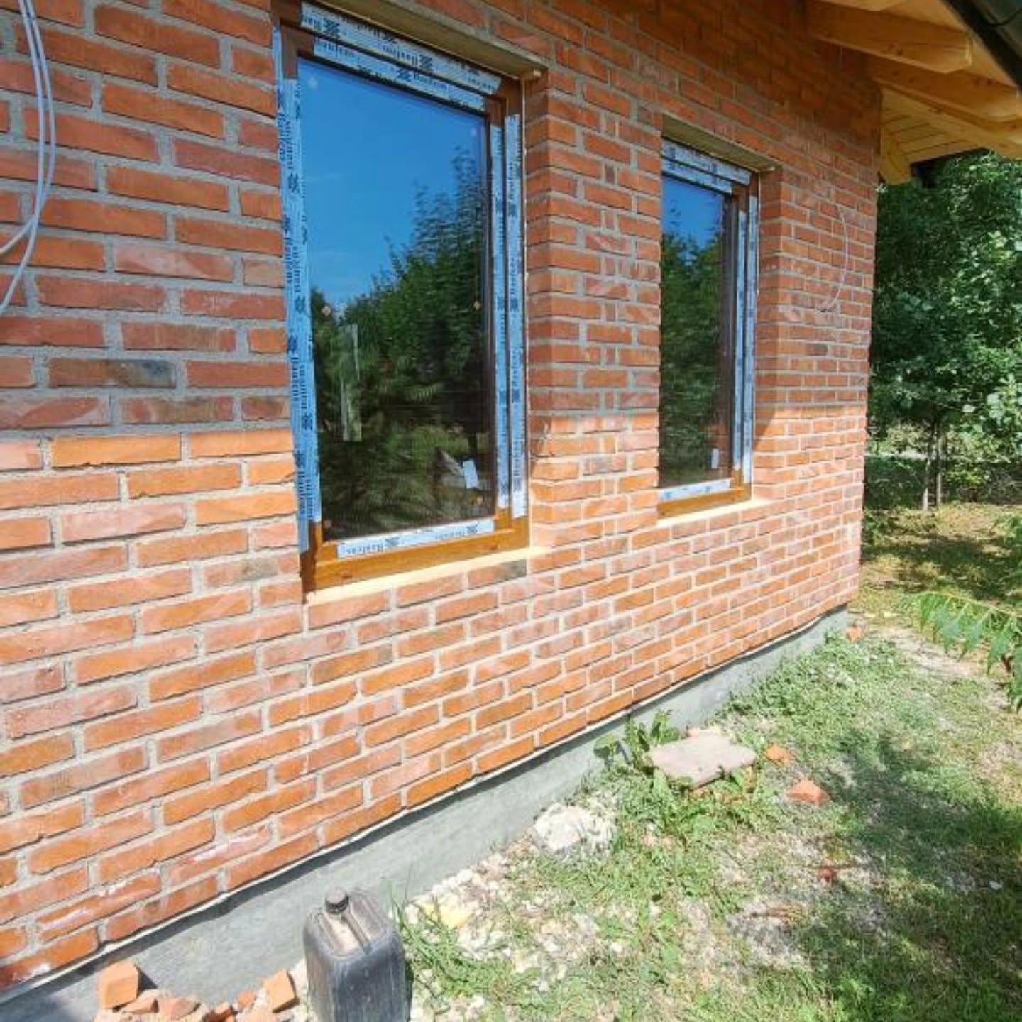 Dva PVC prozora u foliji zlatnog hrasta na fasadi od fasadne opeke